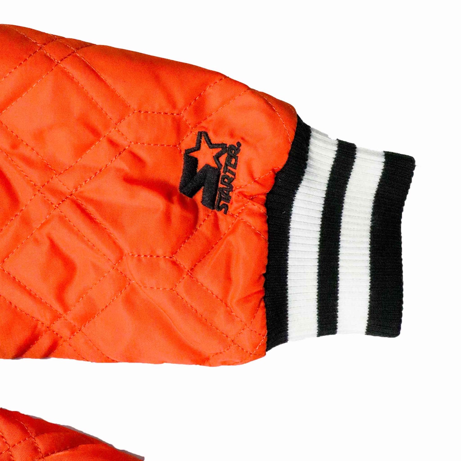 Close-up of an orange quilted jacket with a black and white striped sleeve on a white background