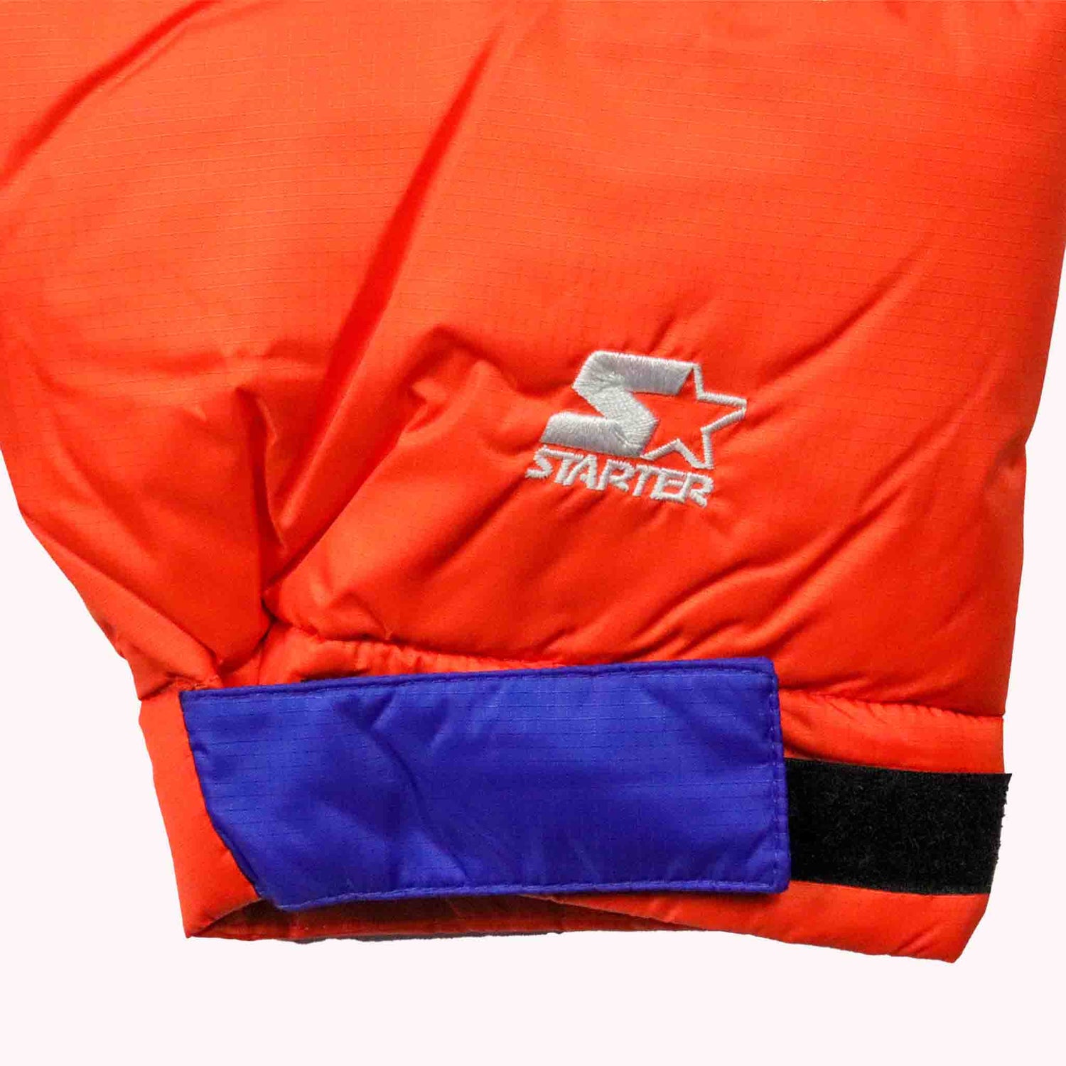 Close-up of a red jacket with a blue patch and 'Starter' logo on a white background