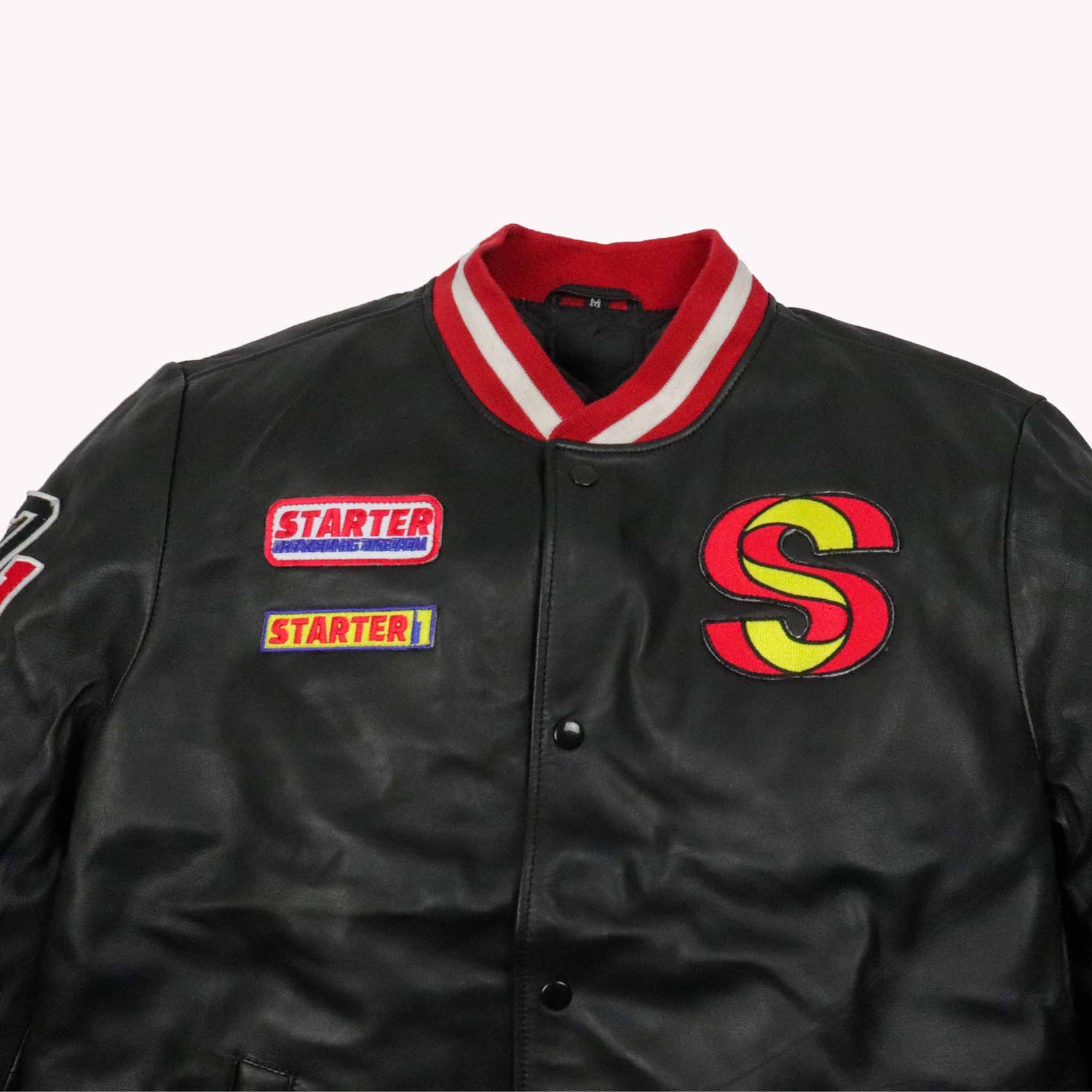 Black varsity jacket with red and yellow 'S' logo and Starter patches on a white background