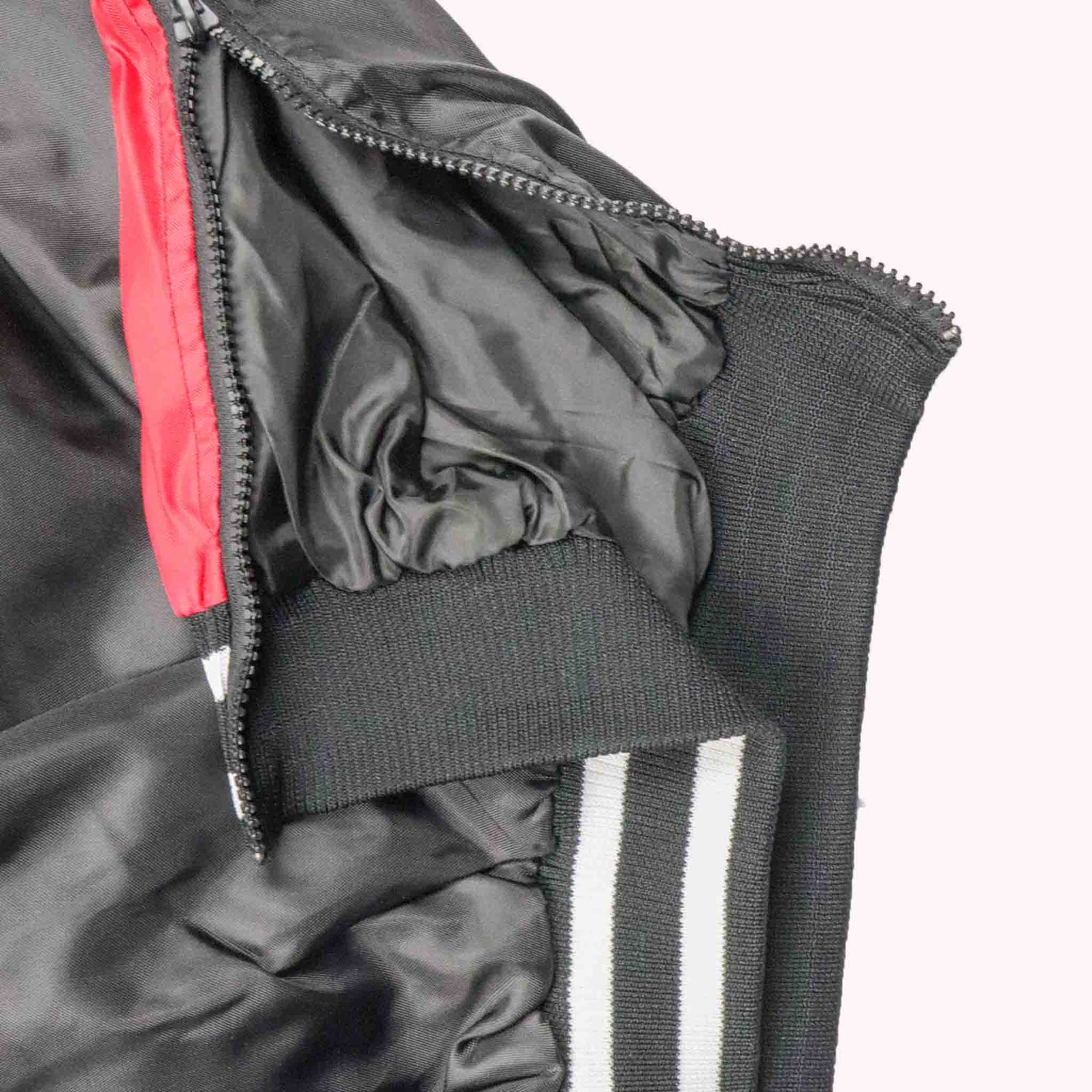 Close-up of a black jacket with red lining and white stripes on a white background