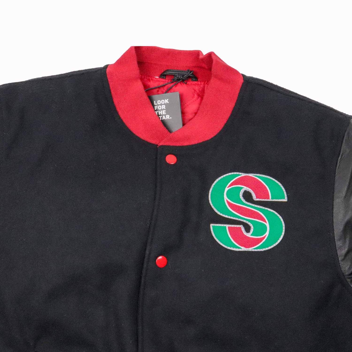 Black letterman jacket with red collar and green and red logo on a white background