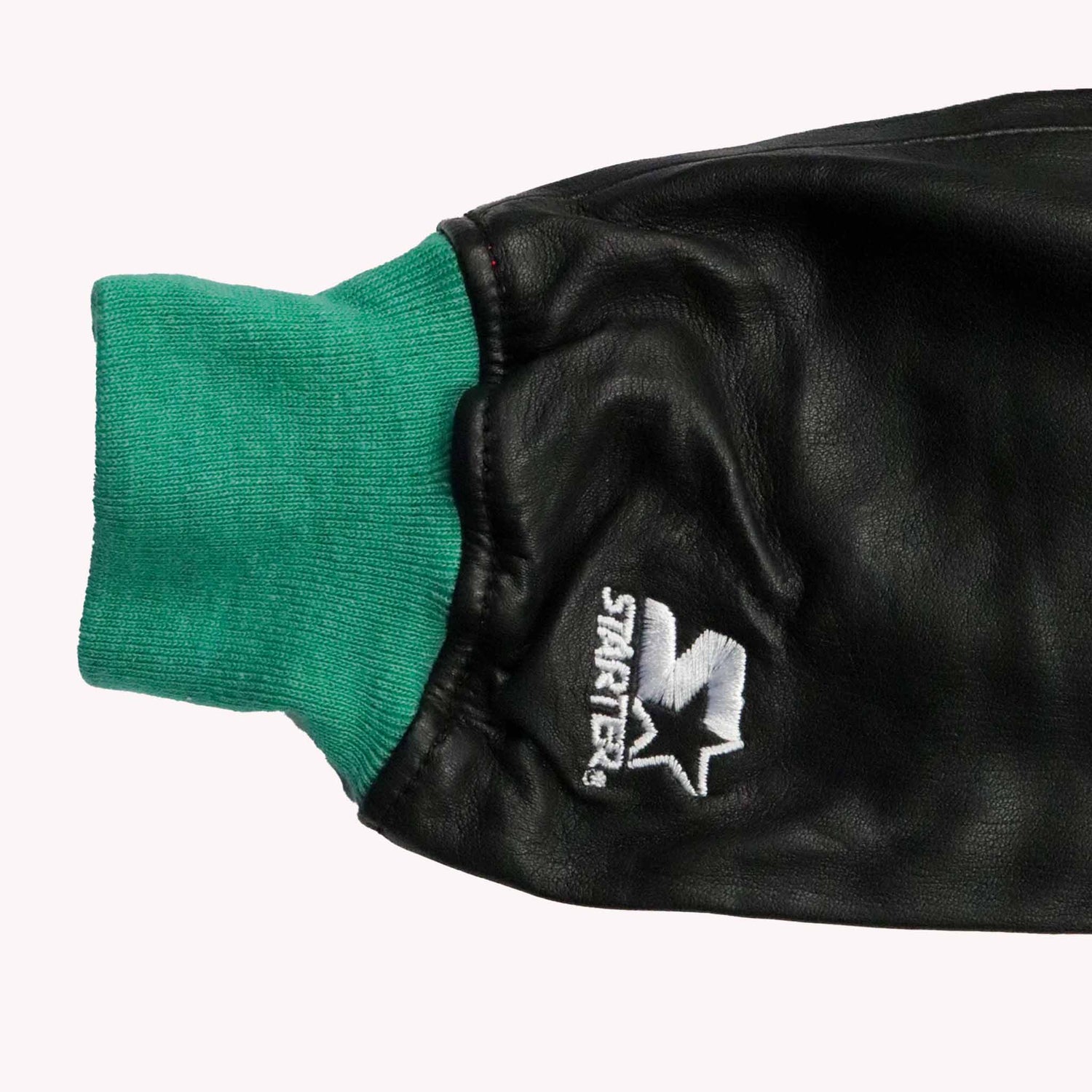 Black leather glove with green cuff and 'Striker' logo on a white background