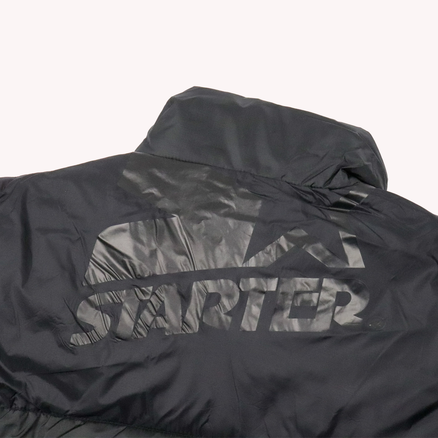 Starter Black Label Down Winter Jackets.
Back upper close Camera view with Starter Logo with Low Opacity on a black surface for a classic Vintage look.
